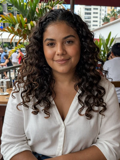 Isabela, 27, Brazilian woman from Rio de Janeiro with curly hair smiling at outdoor cafe - Latin 312 Dating verified profile
